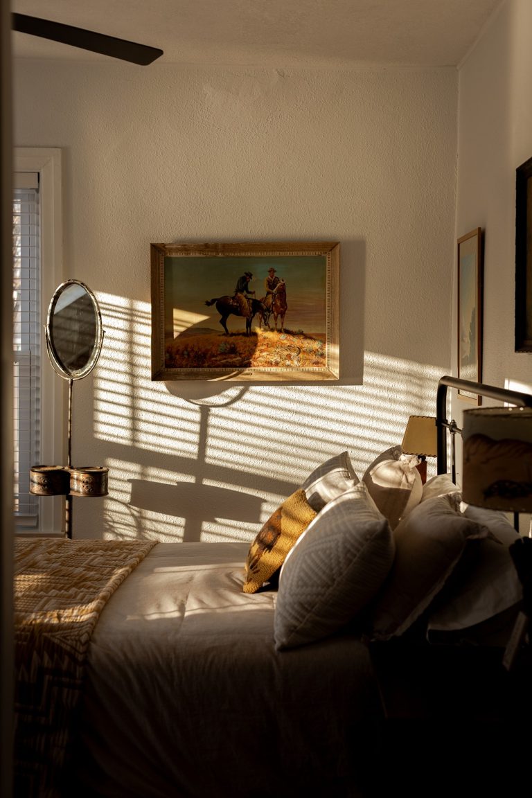 Sunlit bedroom inside Two Lanes Guest House in Le Claire Iowa with western artwork and warm shadows