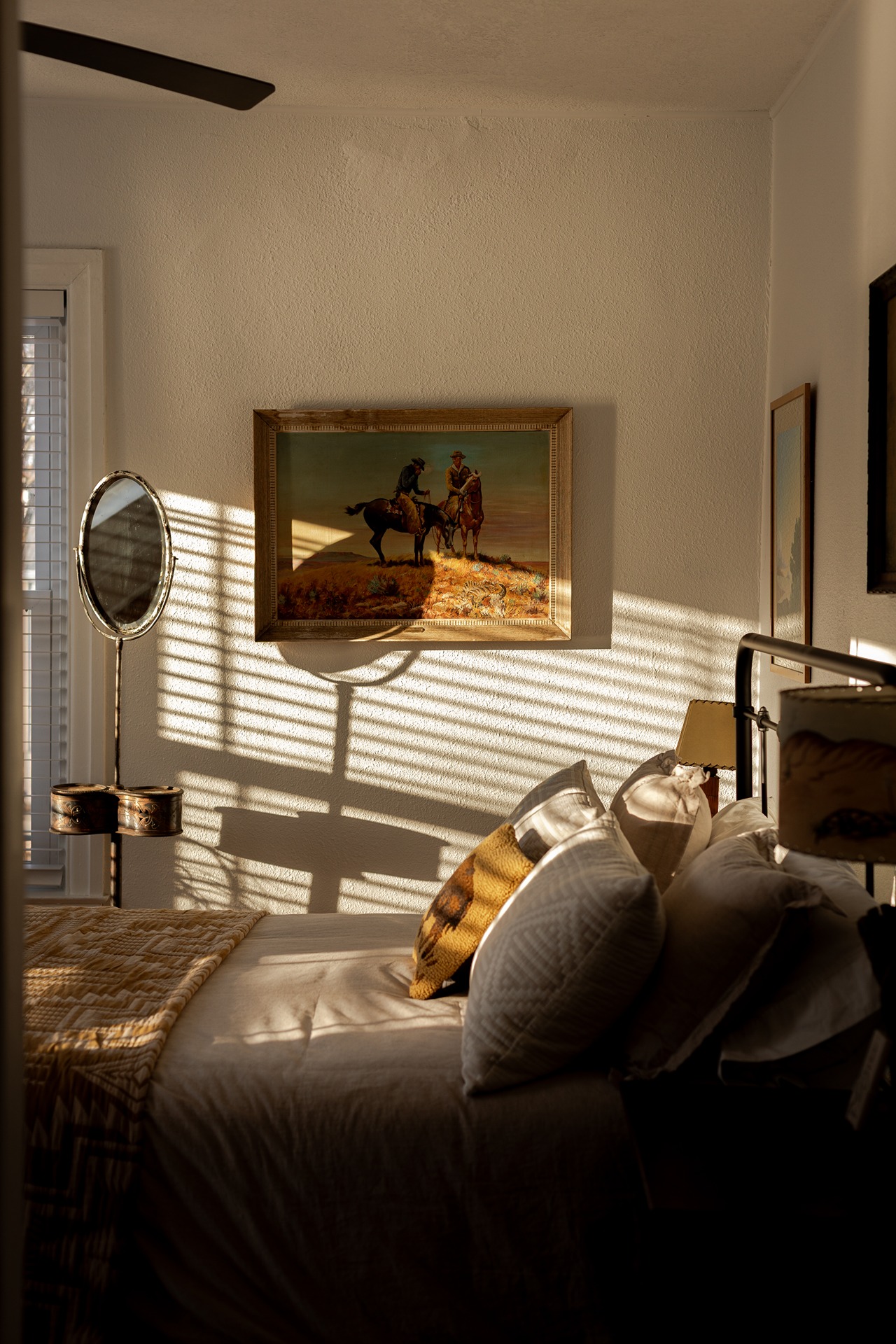 Sunlit bedroom inside Two Lanes Guest House in Le Claire Iowa with western artwork and warm shadows